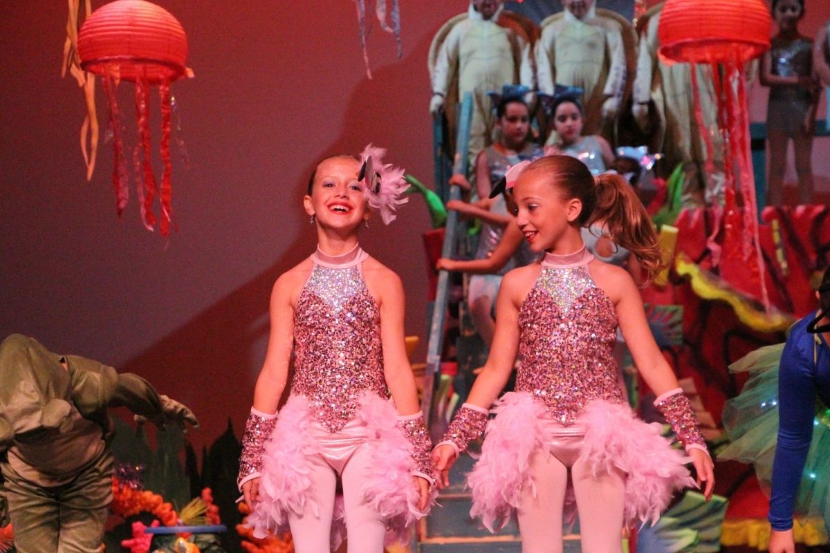 Two female elementary students tin pink glittery and feathered leotards take their bows during Robinson School's production of The Little Mermaid Jr.