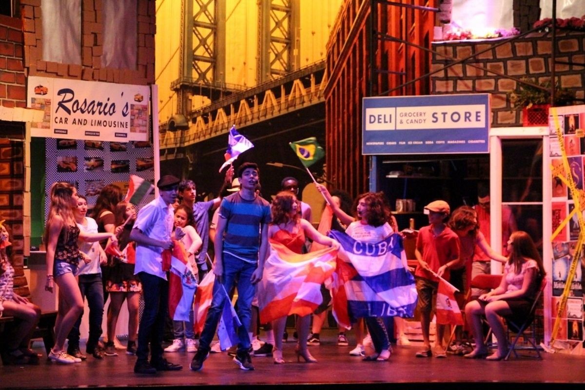 A scene from Robinson School's production of In The Heights, with flags from multiple Latin American countries flown by students.