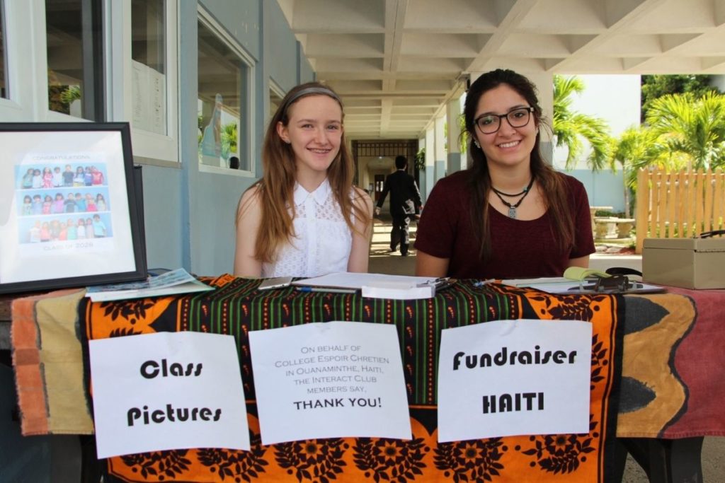Two female students of the Interact Club in casual wear table to fundraise for Haitians.