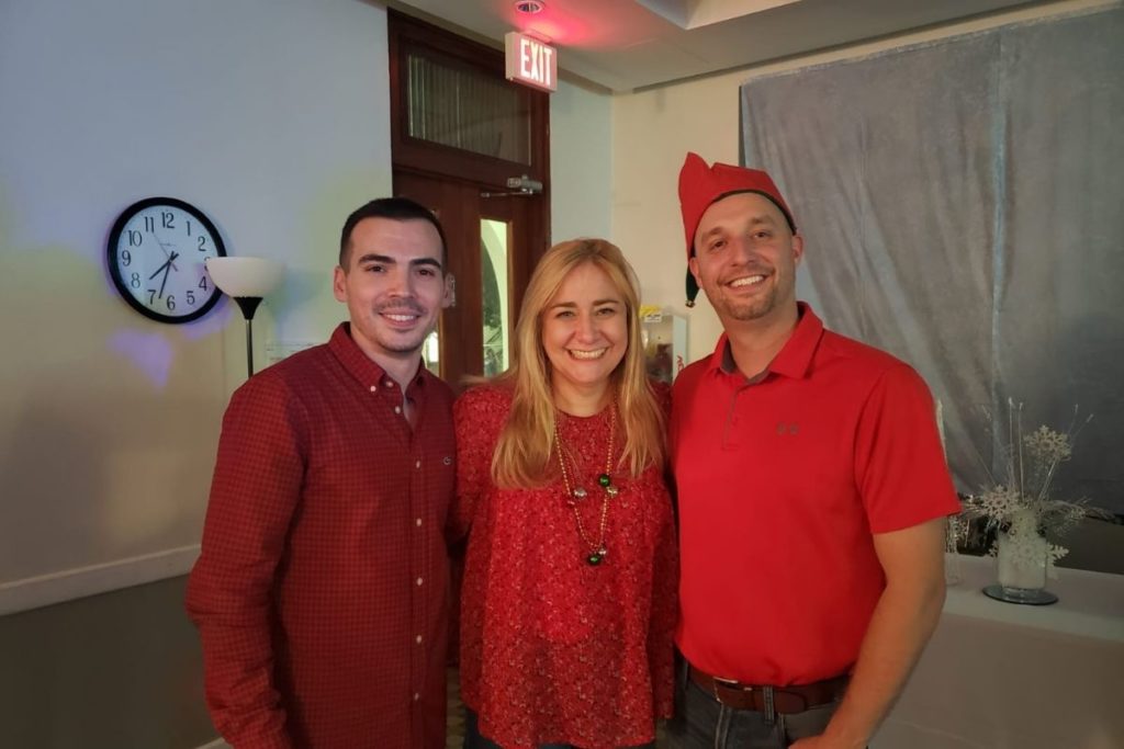 (Left to Right) Middle & Upper School Division Head Luis Fortes, Head of School Cindy Ogg and Academic Dean Thomas Novak. They are all wearing red and are hugging.
