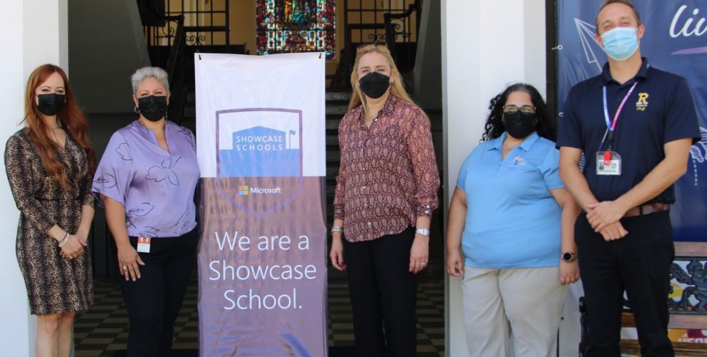 Members of Robinson School administration alongside Microsoft representatives stand next to a banner that states 'We are a Showcase School'.