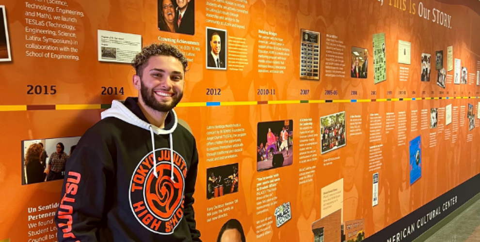 Alejandro G. Dávila Hurtado standing in front of a timeline wall at El Instituto of the University of Connecticut