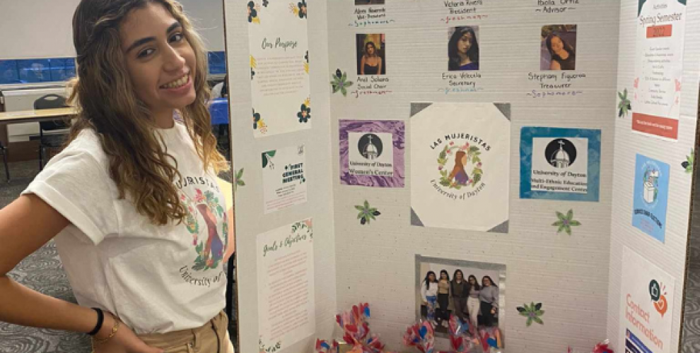 Victoria Rivera Nazario standing in front of a poster board for her feminist Latinx organization Las Mujeristas at University of Dayton