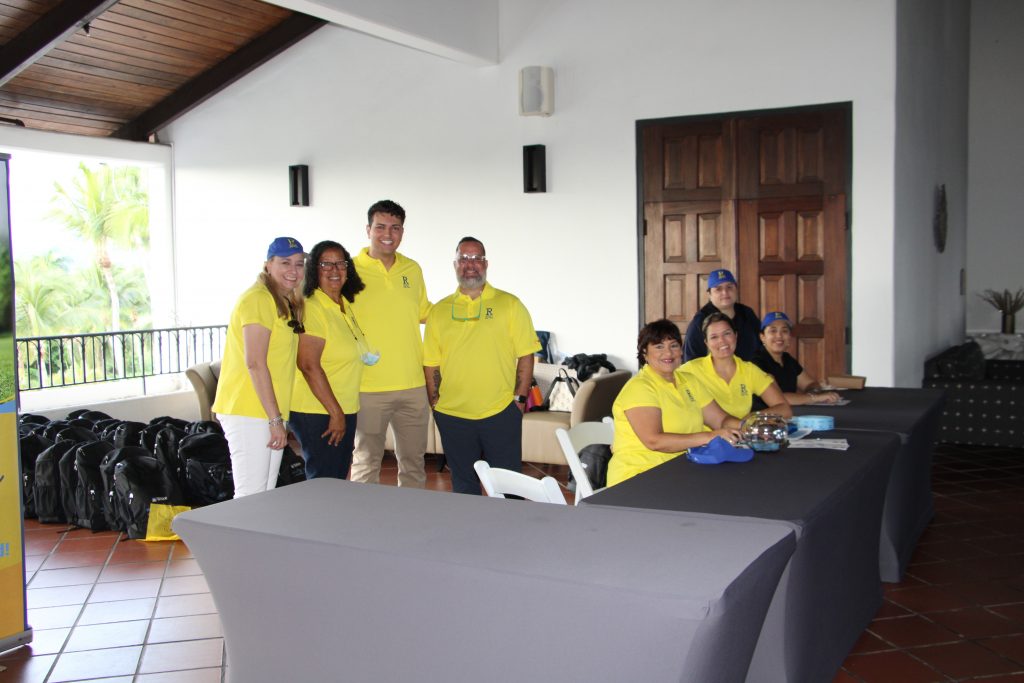 Robinson School staff members in neon yellow shirts pose at the registration tables for the Golf Fundraiser.